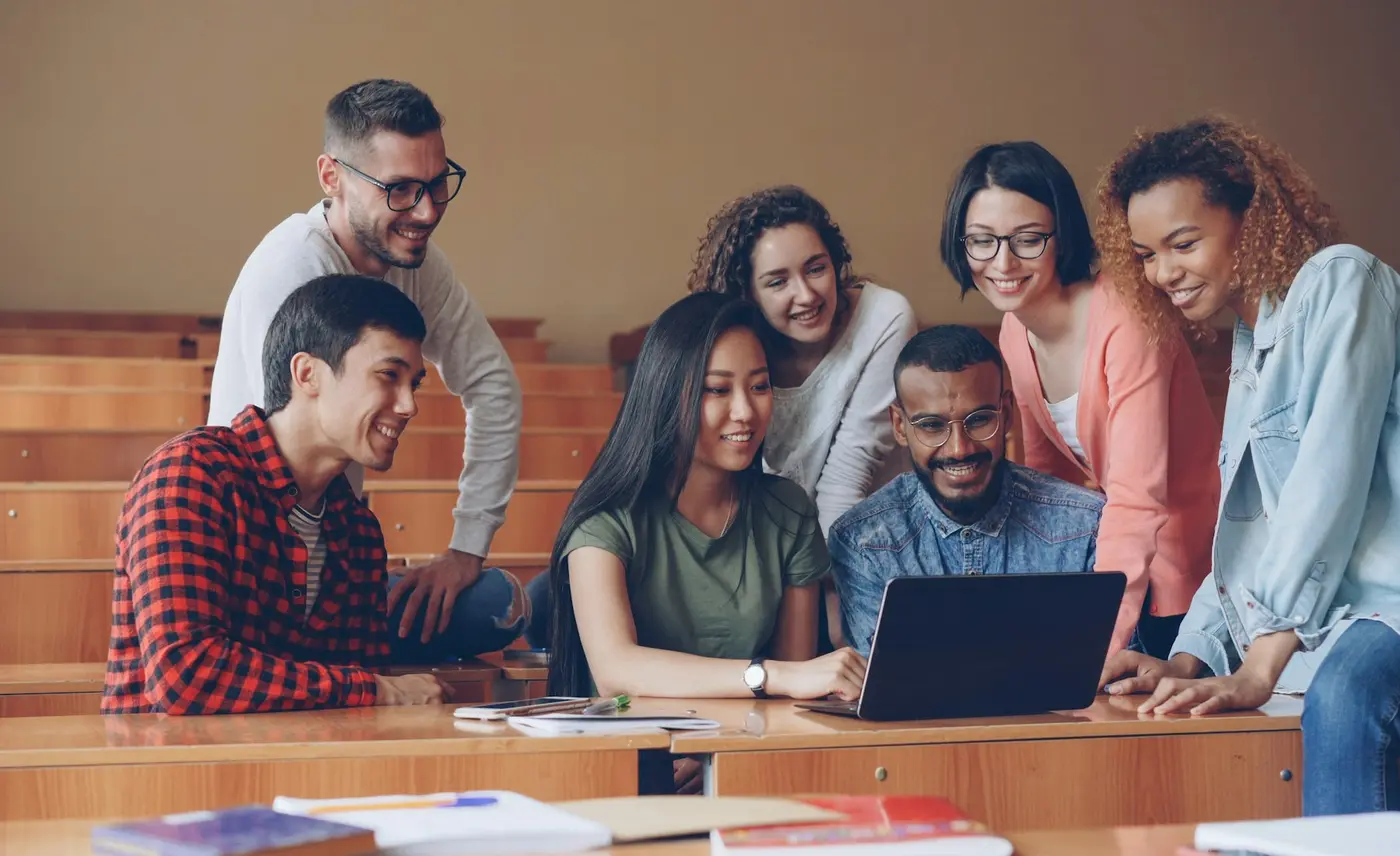 Diverse university students collaborating around a laptop