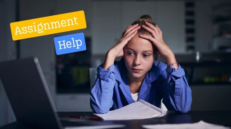 A stressed student sitting at a desk with hands on head, looking at a laptop and open notebook, symbolising the challenges of managing assignments.